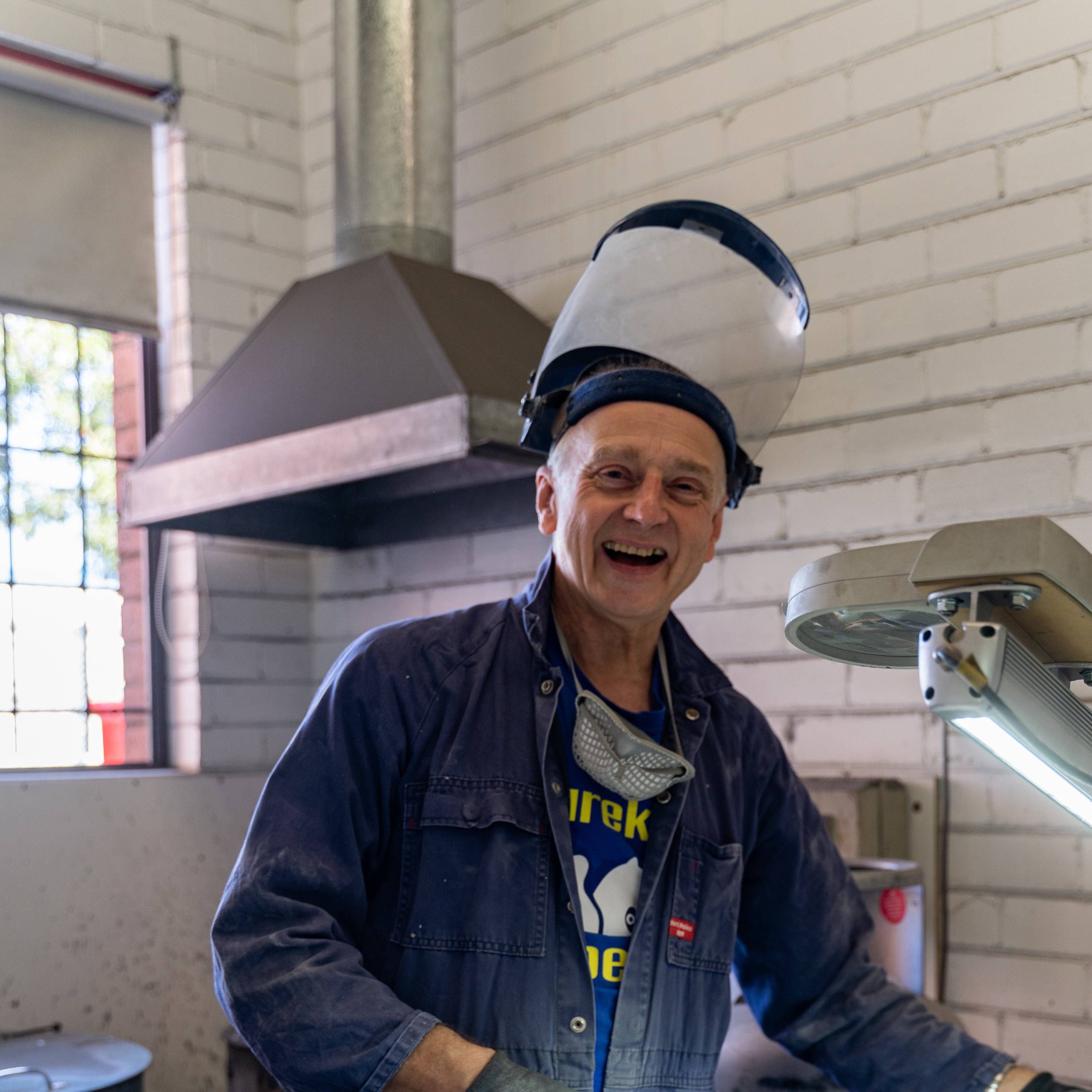 Person wearing a welding helmet and gloves in a workshop setting